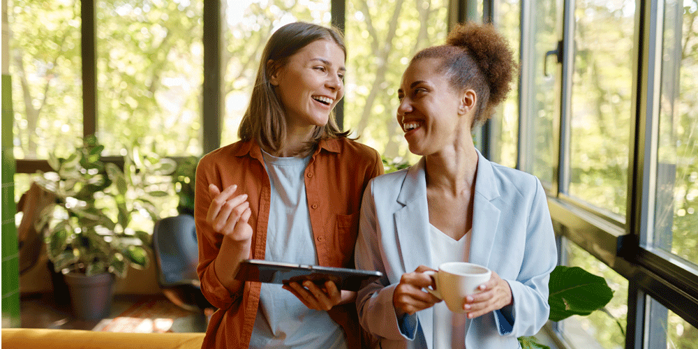 Two best friends smiling together at work.